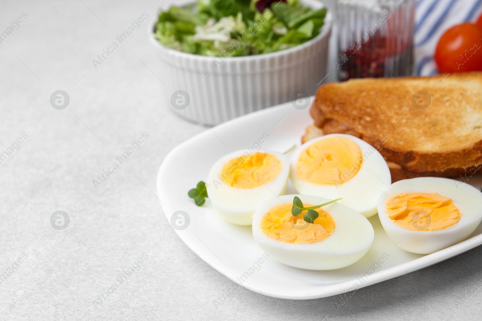 Photo of Hard boiled eggs with bread on light table, closeup. Space for text