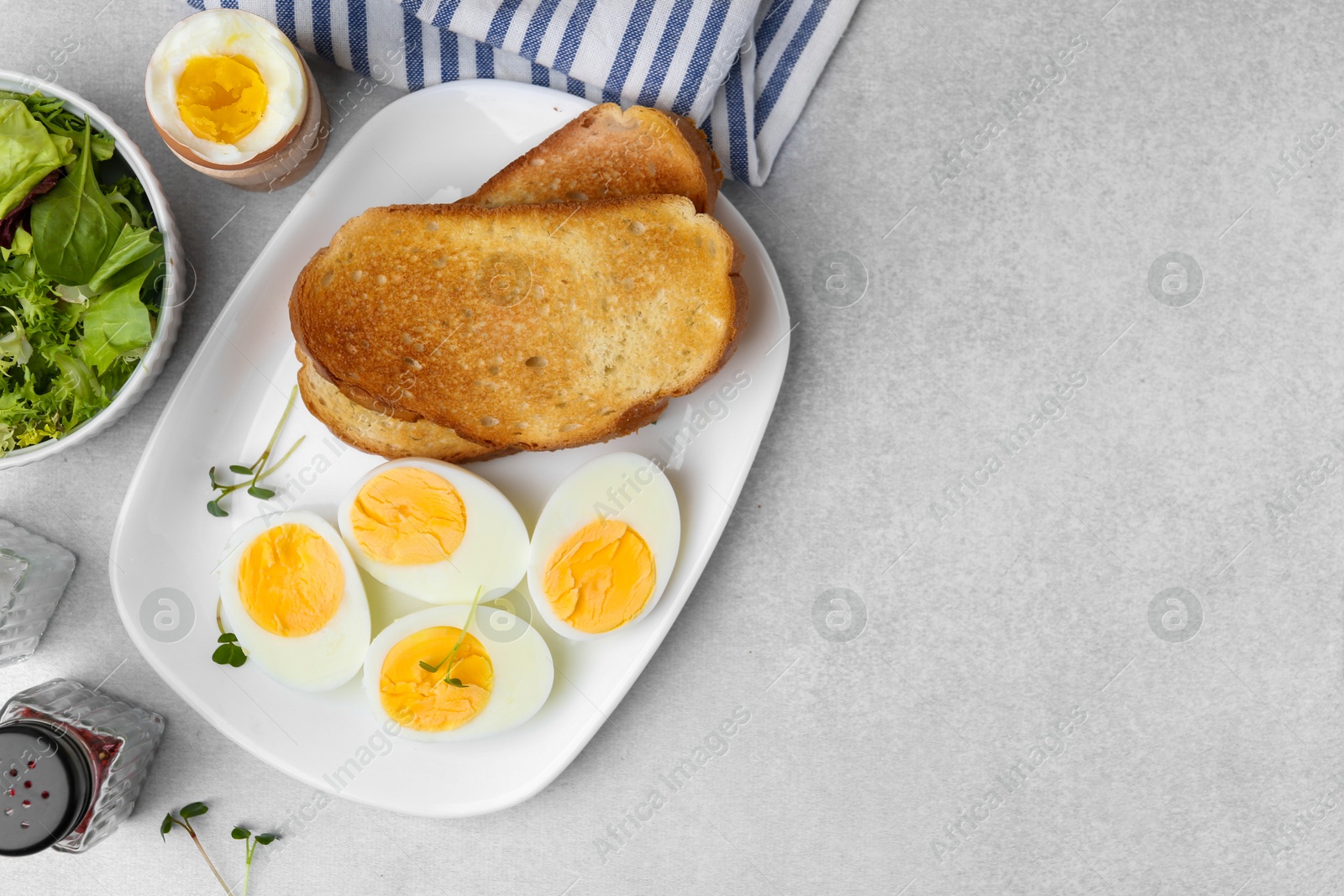 Photo of Hard boiled eggs with bread on light table, flat lay. Space for text