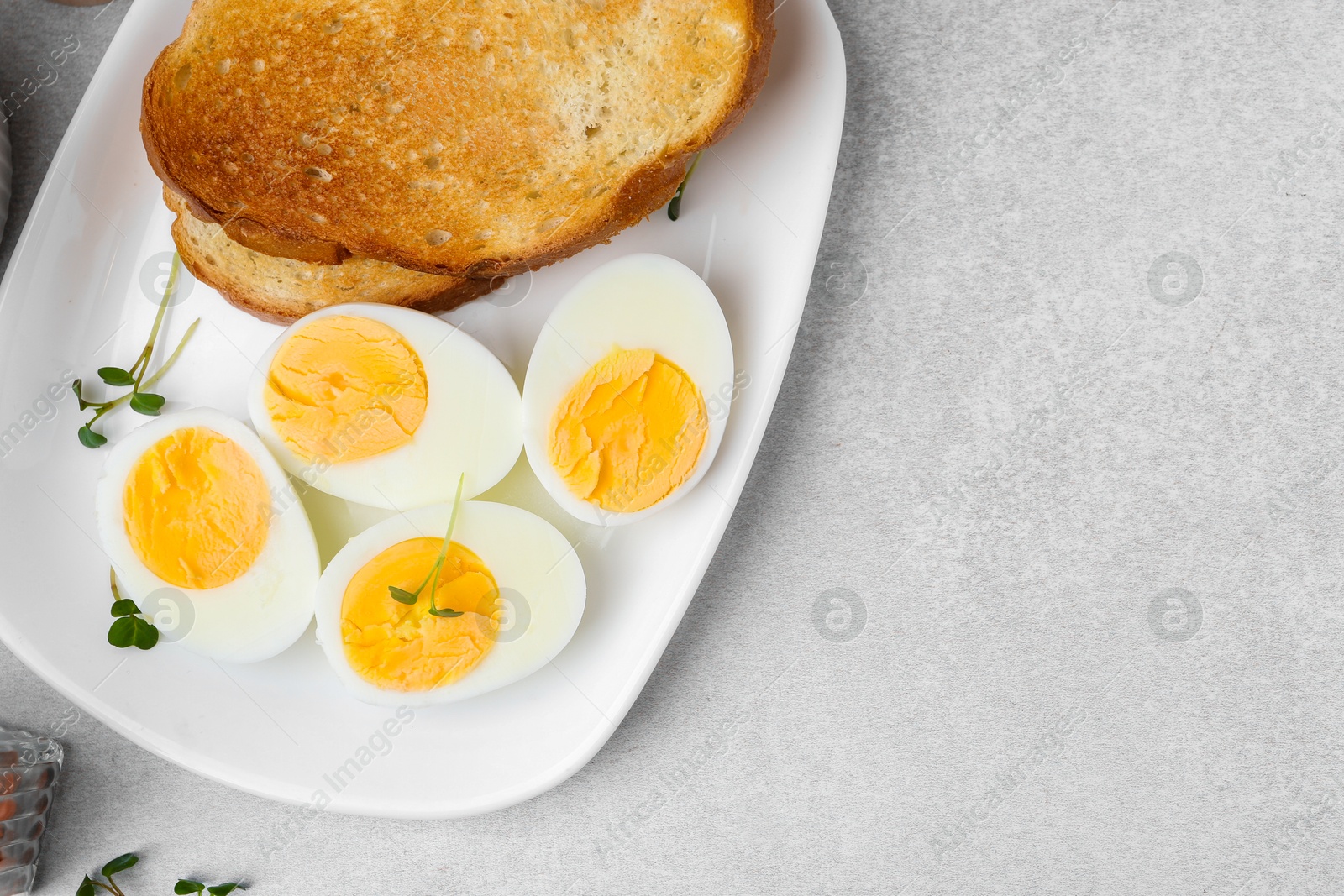 Photo of Hard boiled eggs with bread on light table, top view. Space for text