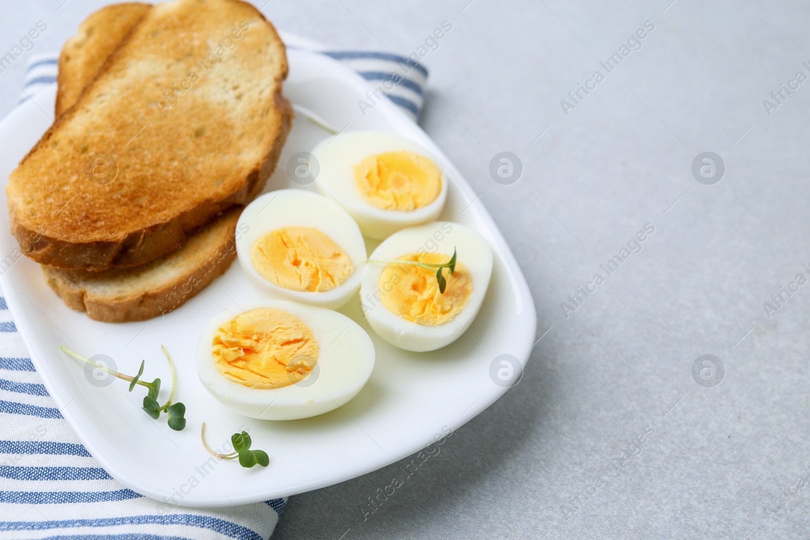 Photo of Hard boiled eggs with bread on light table, closeup. Space for text