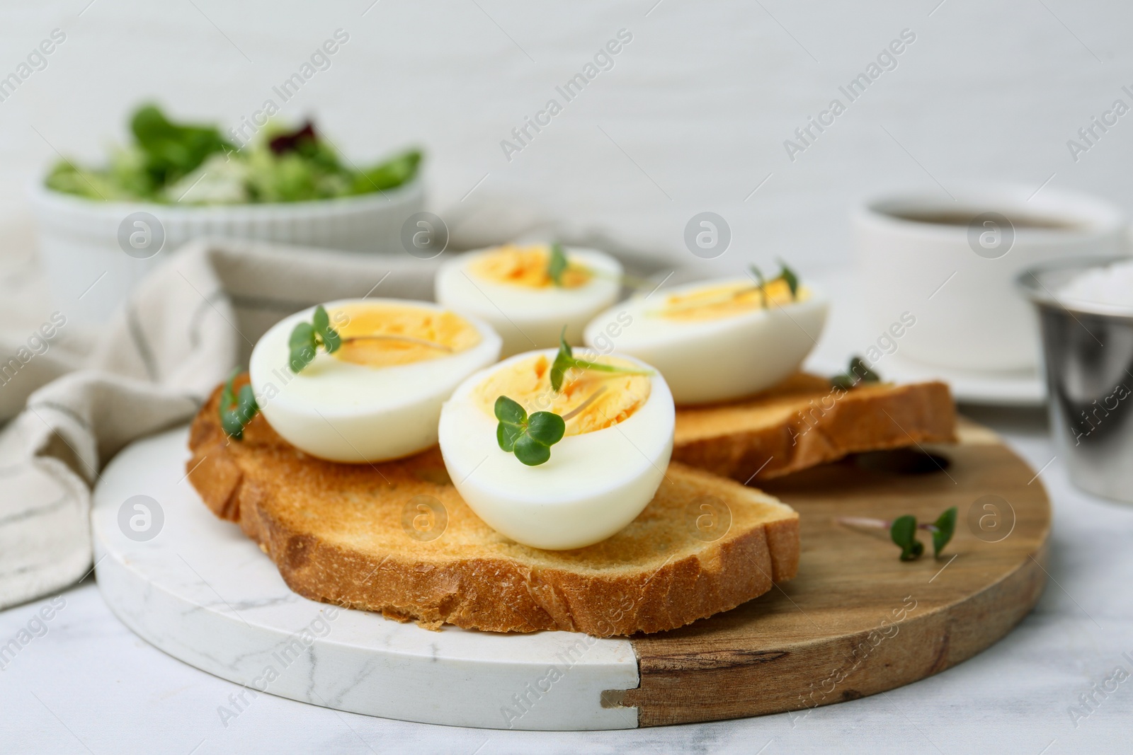 Photo of Sandwiches with hard boiled eggs on white marble table, closeup