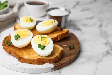 Photo of Sandwiches with hard boiled eggs on white marble table, closeup. Space for text