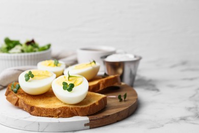 Photo of Sandwiches with hard boiled eggs on white marble table, closeup. Space for text