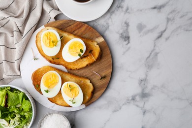 Photo of Sandwiches with hard boiled eggs on white marble table, flat lay. Space for text