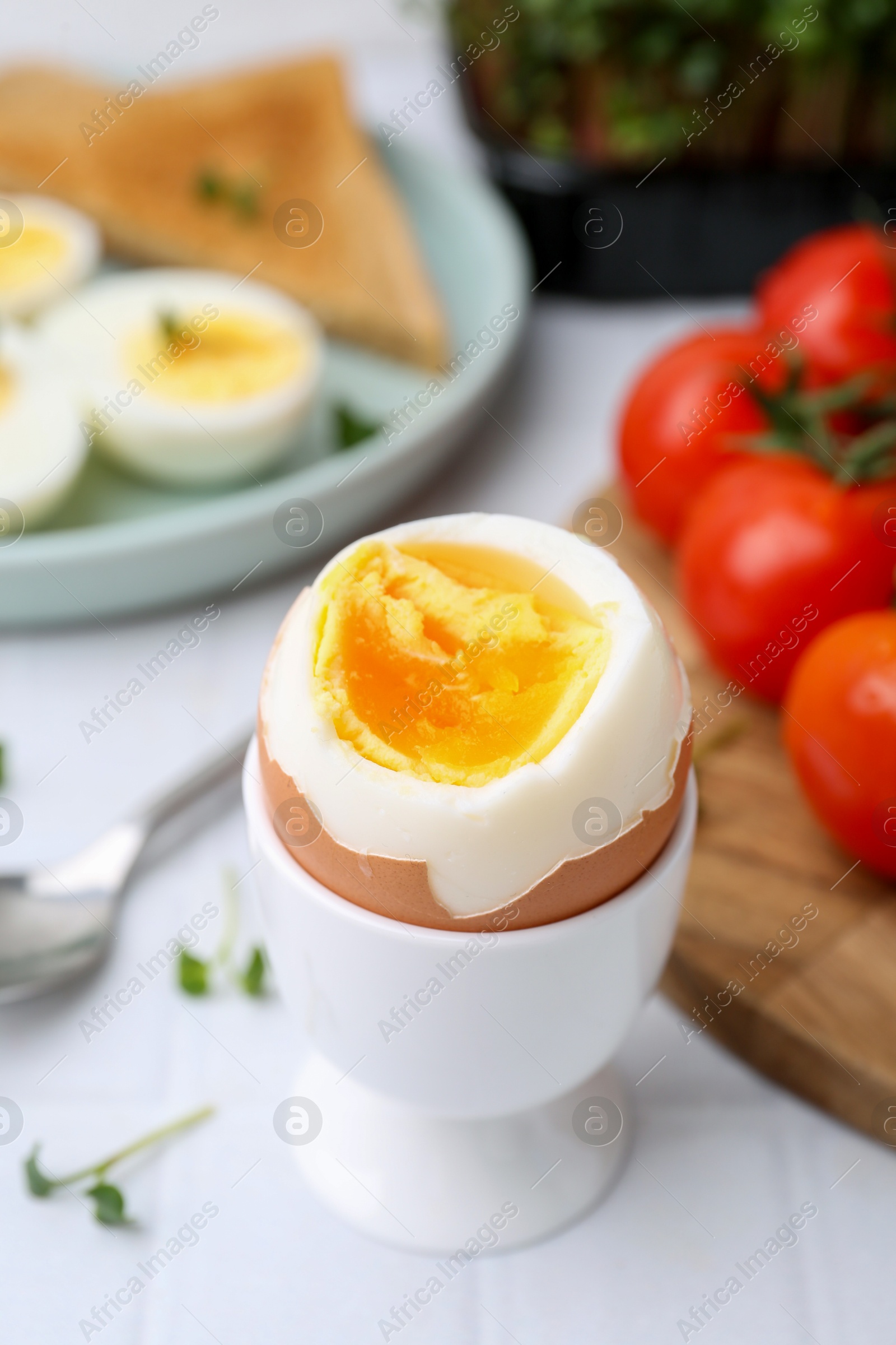 Photo of Soft boiled egg on white tiled table, closeup