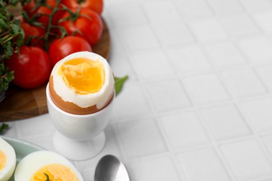 Photo of Soft boiled egg on white tiled table, closeup. Space for text