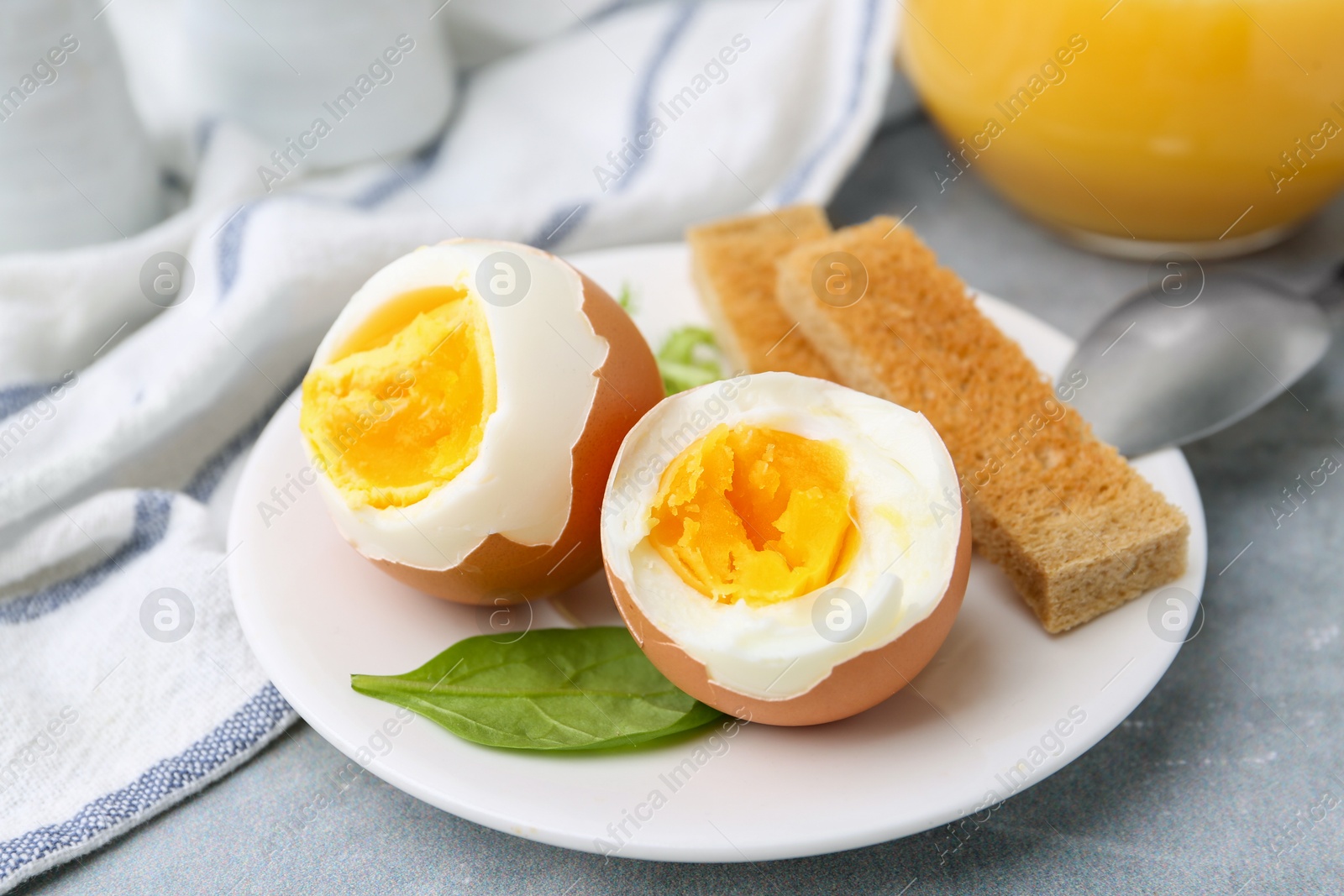 Photo of Soft boiled eggs with bread on grey table, closeup