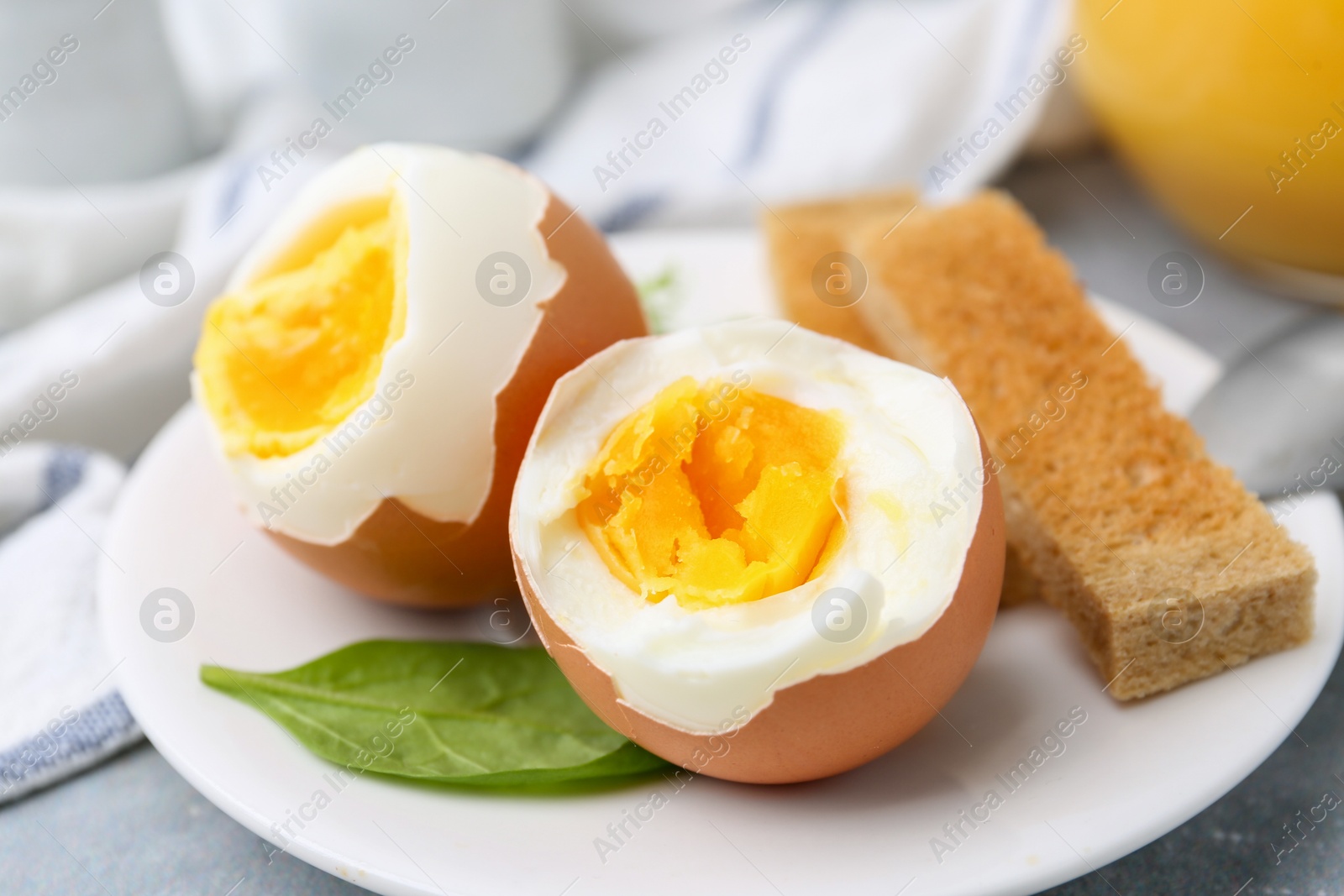 Photo of Soft boiled eggs with bread on grey table, closeup