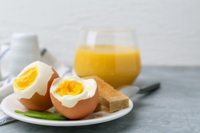 Photo of Soft boiled eggs with bread on grey table, closeup. Space for text