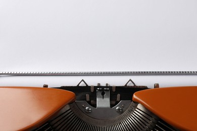 Photo of Vintage typewriter with sheet of paper as background, closeup. Space for text