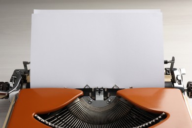 Photo of Vintage typewriter with sheet of paper on wooden table, closeup. Space for text