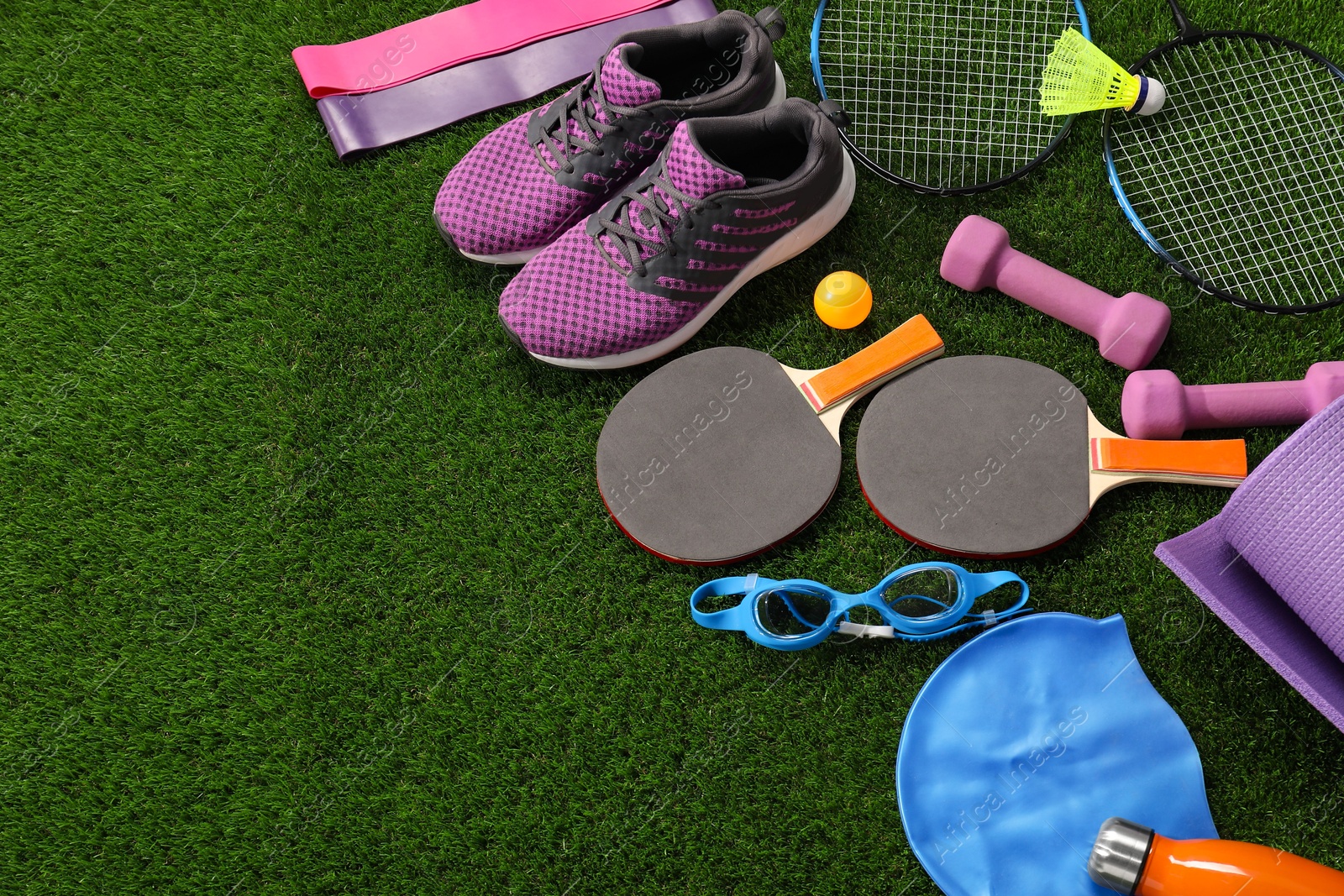 Photo of Different sport equipment on artificial grass, above view. Space for text