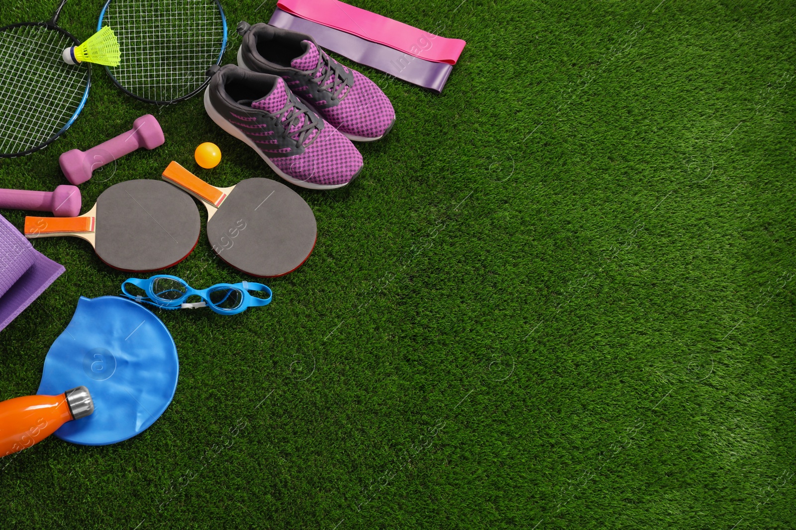 Photo of Different sport equipment on artificial grass, above view. Space for text