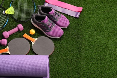 Photo of Different sport equipment on artificial grass, above view. Space for text