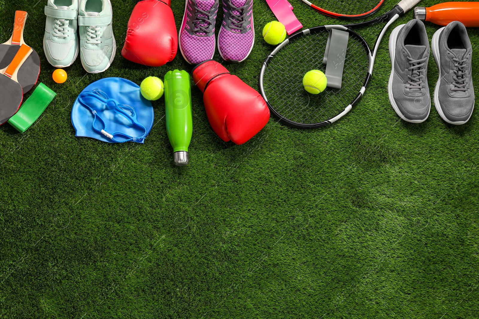 Photo of Different sport equipment on artificial grass, flat lay. Space for text