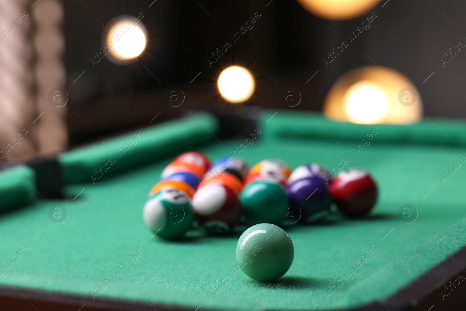 Photo of Billiard balls in triangle on green table indoors, closeup. Space for text