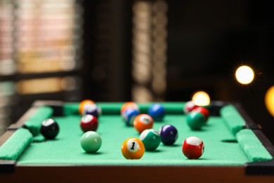 Photo of Many colorful billiard balls on green table indoors, closeup