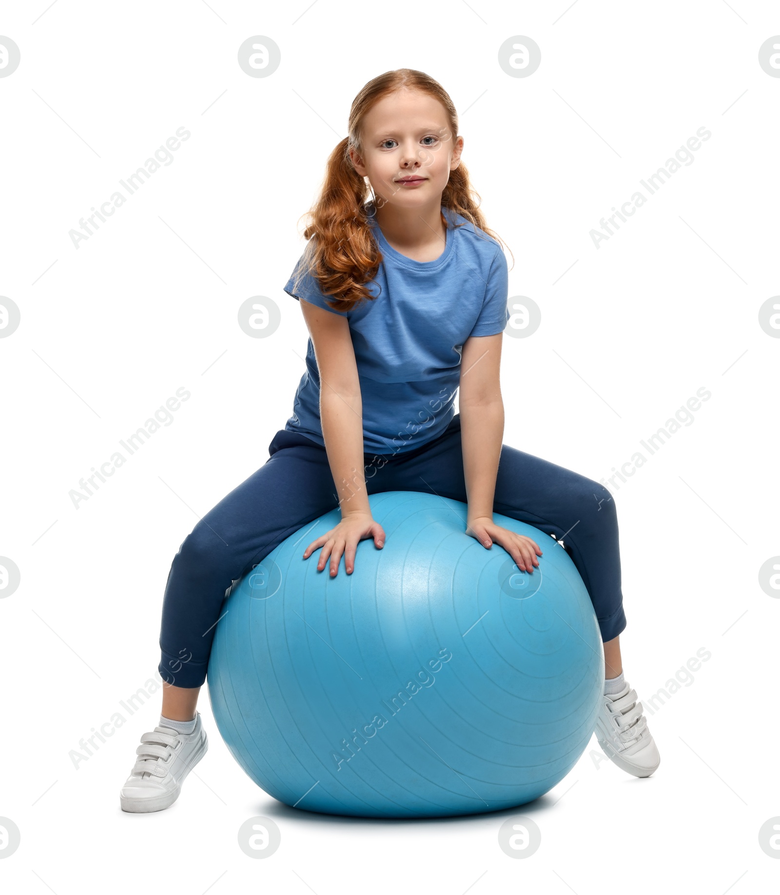 Photo of Cute little girl sitting on fitness ball against white background