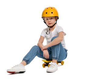 Photo of Little girl in helmet sitting on penny board against white background