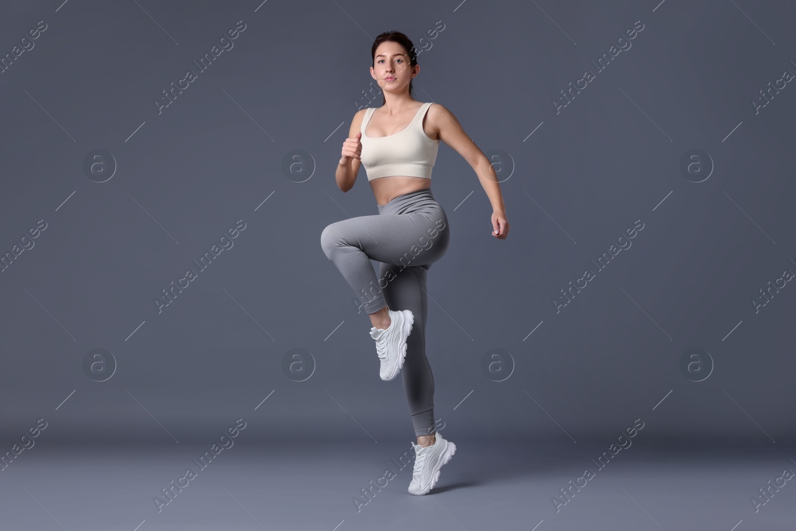 Photo of Woman in sportswear exercising on grey background