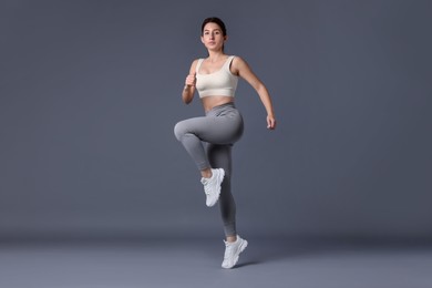 Photo of Woman in sportswear exercising on grey background