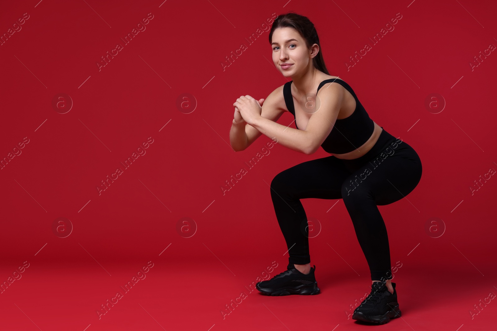 Photo of Woman in sportswear exercising on red background, space for text