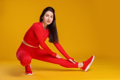 Photo of Woman in sportswear exercising on orange background