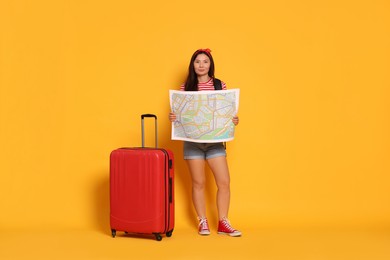 Photo of Happy traveller with map and suitcase on yellow background