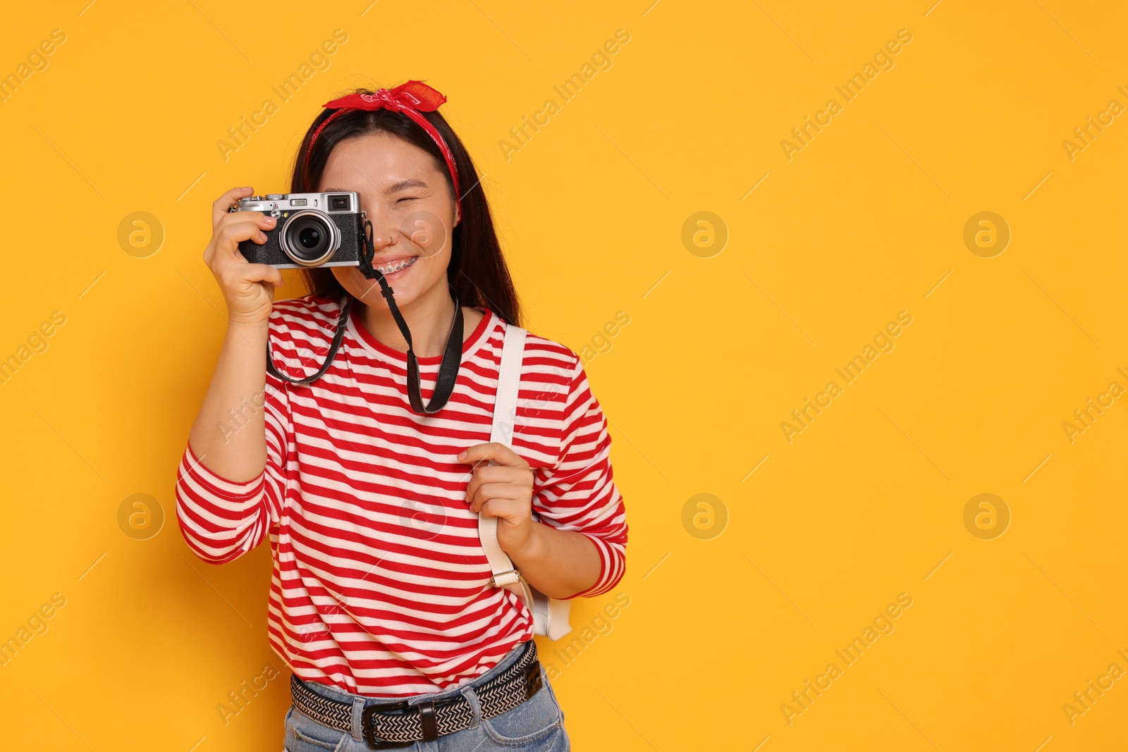 Photo of Happy traveller with camera on yellow background. Space for text