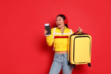 Photo of Happy traveller with passport and suitcase on red background. Space for text