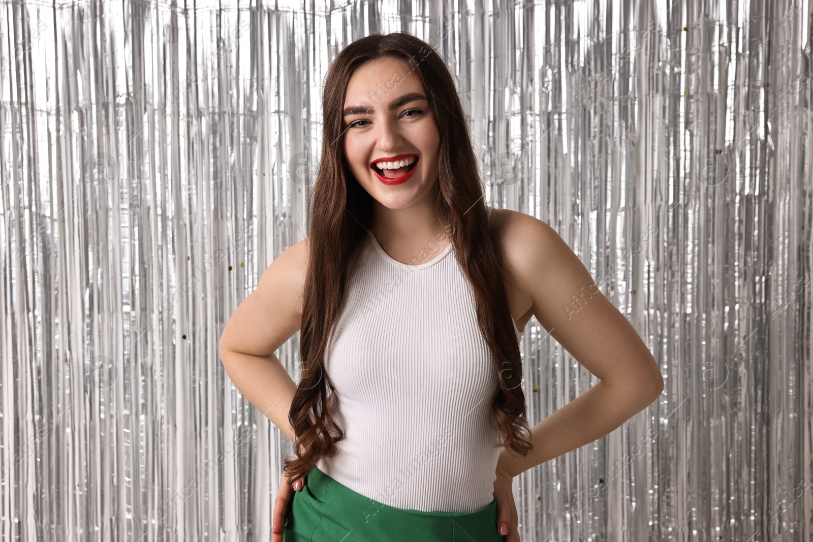 Photo of Portrait of happy young woman against silver foil curtain