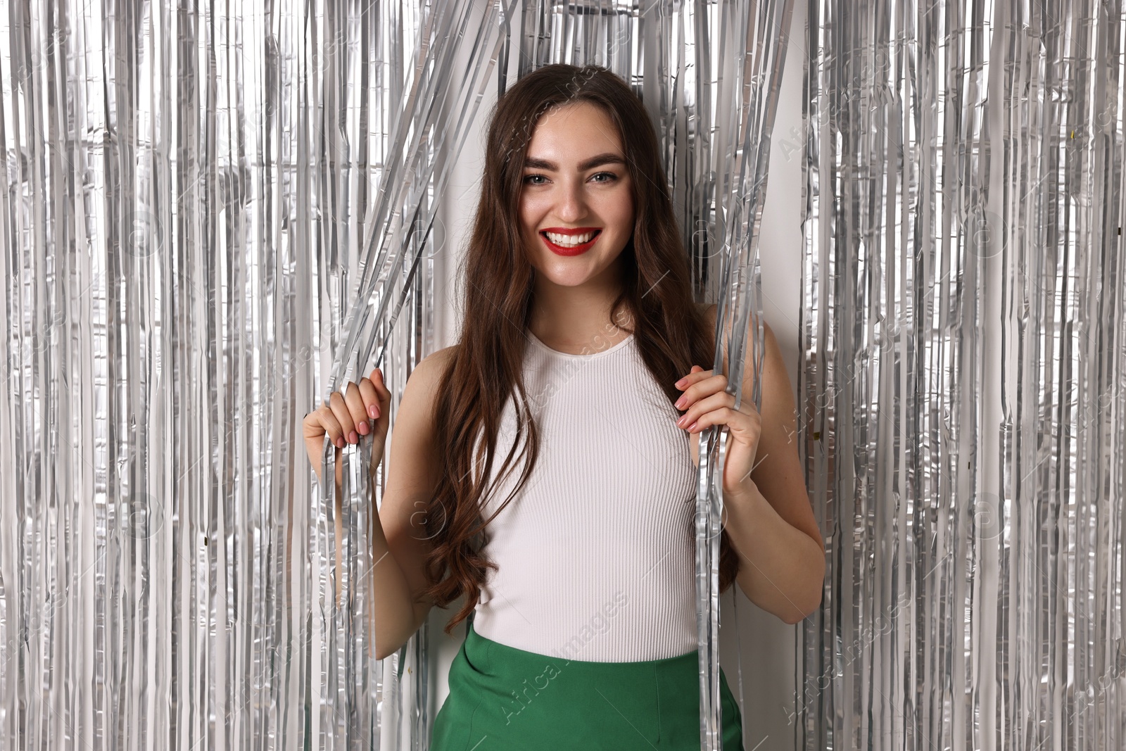 Photo of Portrait of happy young woman near silver foil curtain against white background