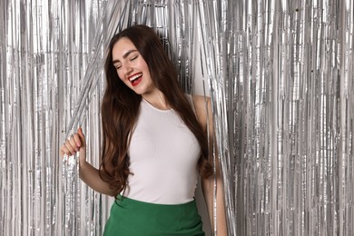 Photo of Portrait of happy young woman near silver foil curtain against white background