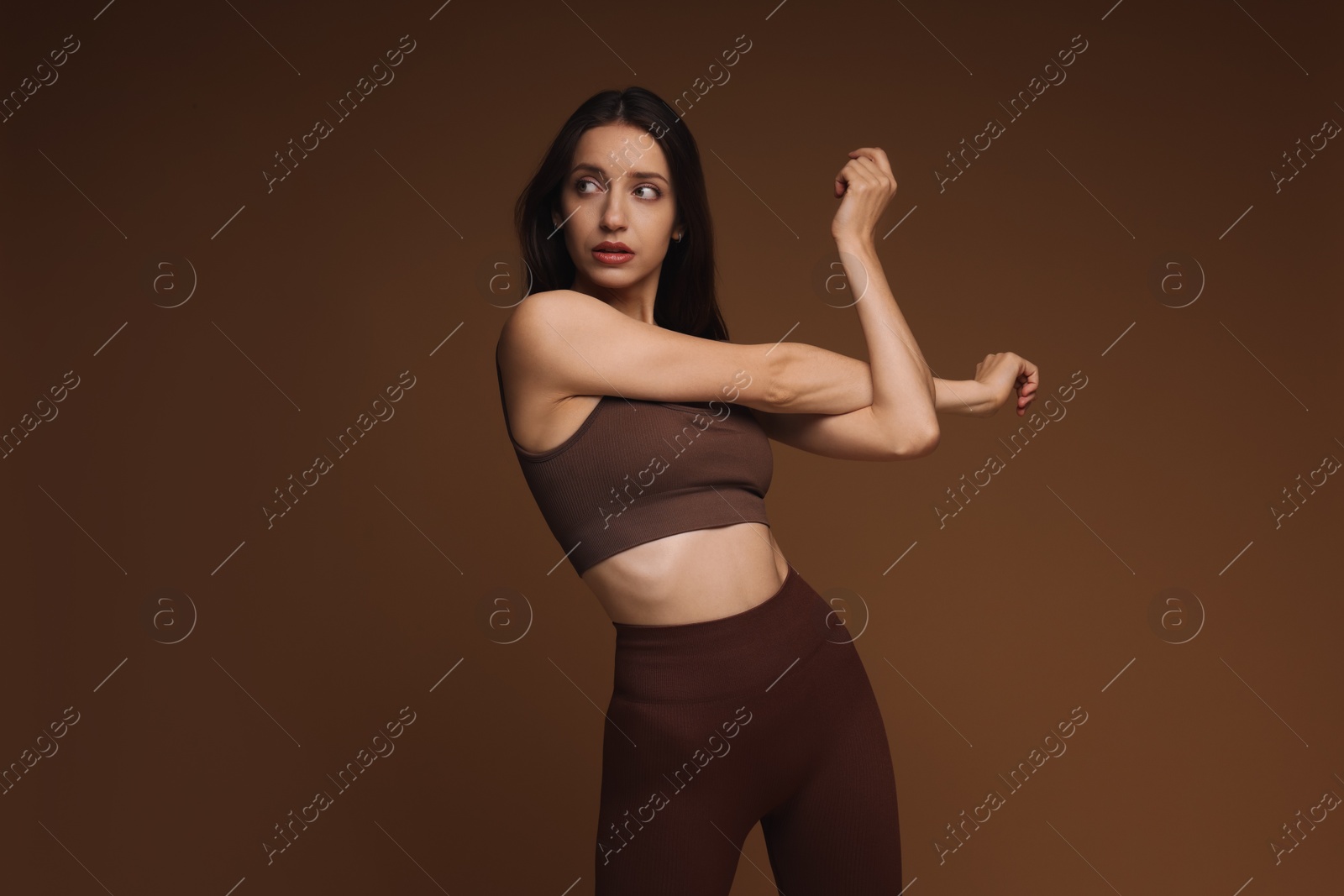 Photo of Beautiful woman in stylish sportswear on brown background