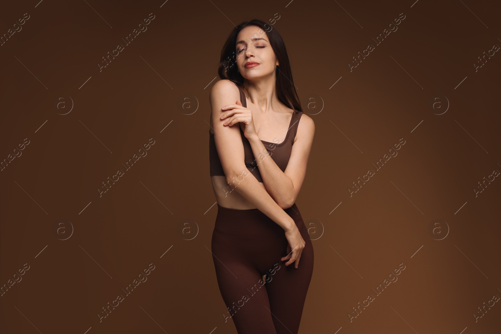 Photo of Beautiful woman in stylish sportswear on brown background