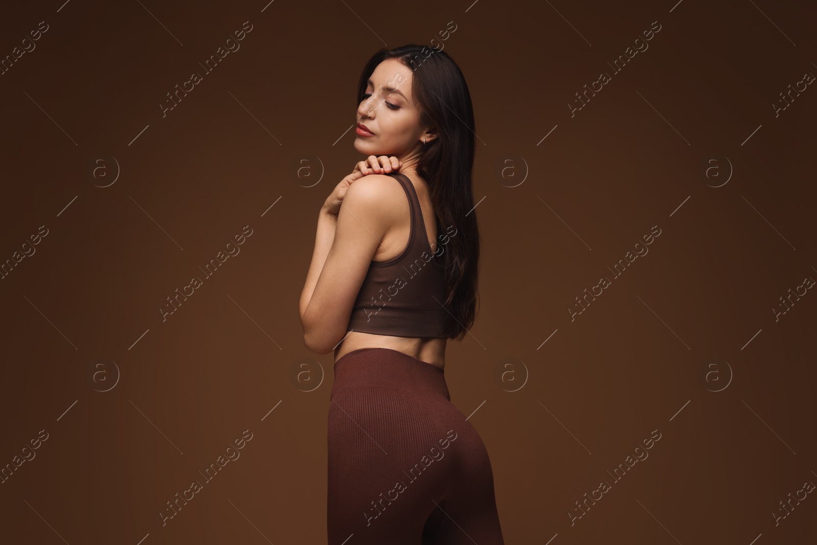 Photo of Beautiful woman in stylish sportswear on brown background