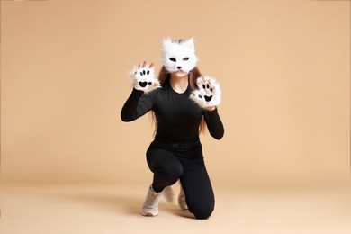 Photo of Quadrobics. Girl wearing cat mask and gloves on beige background