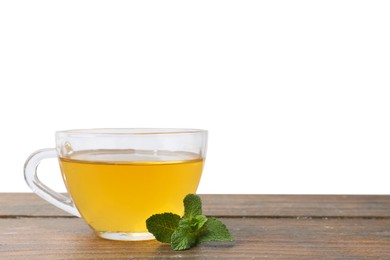 Photo of Aromatic mint tea in glass cup and fresh leaves on wooden table against white background, space for text