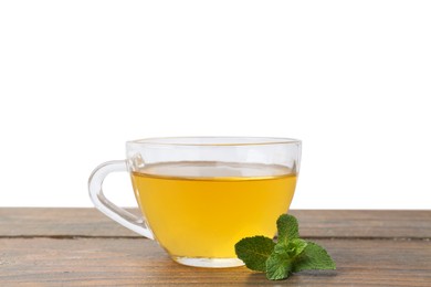 Photo of Aromatic mint tea in glass cup and fresh leaves on wooden table against white background