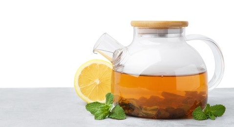 Photo of Aromatic mint tea in glass teapot, fresh leaves and lemon on light gray table against white background, space for text