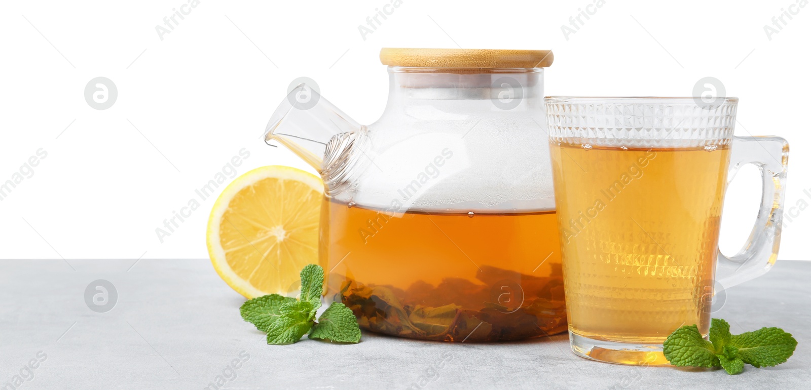 Photo of Aromatic mint tea, fresh leaves and lemon on light gray table against white background, space for text