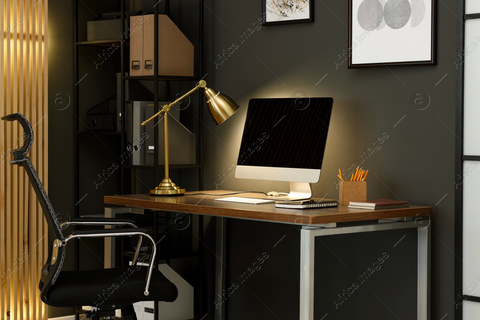 Photo of Comfortable workplace with computer and lamp on wooden desk in home office