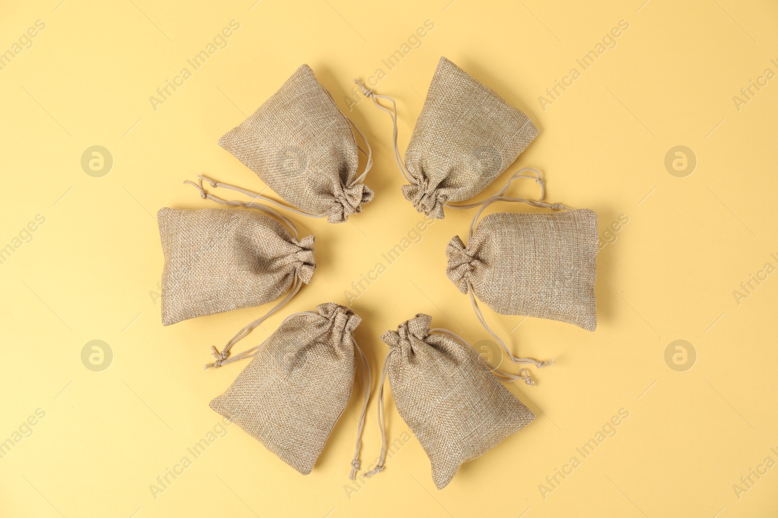 Photo of Many burlap bags on yellow background, flat lay