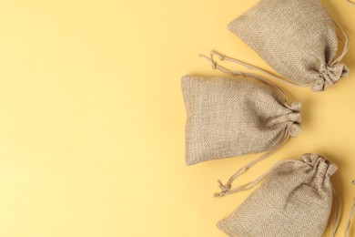 Photo of Natural burlap bags on yellow background, flat lay. Space for text