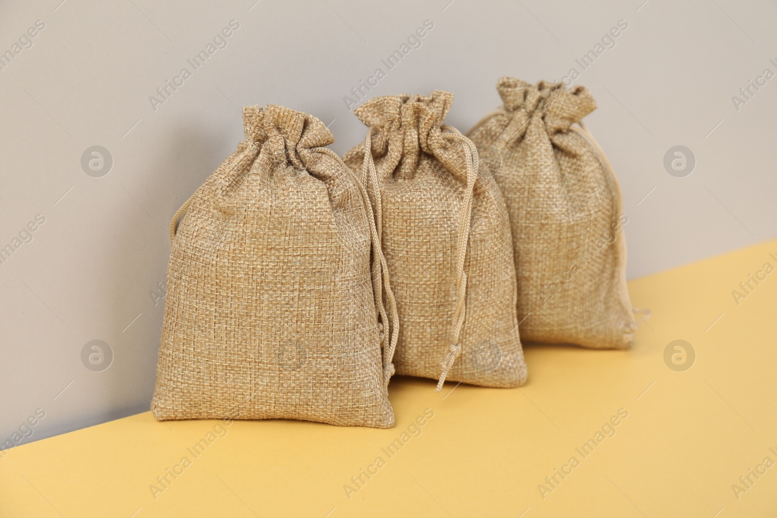 Photo of Three natural burlap bags on color background