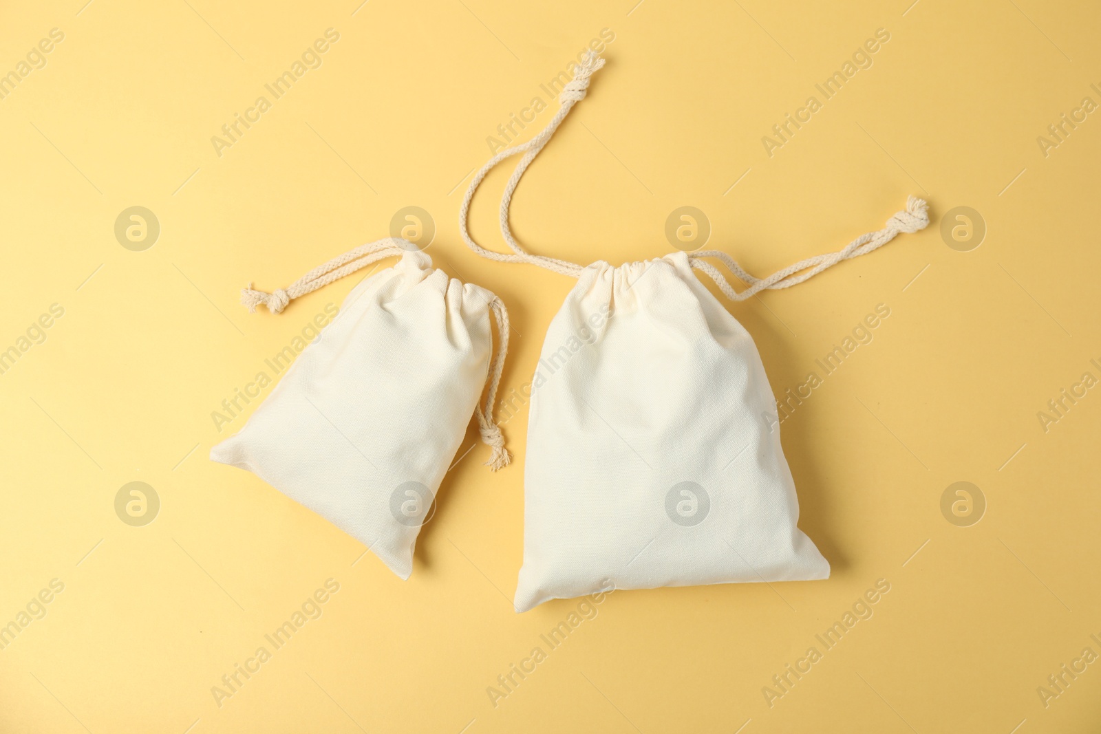 Photo of Two cotton bags on yellow background, flat lay