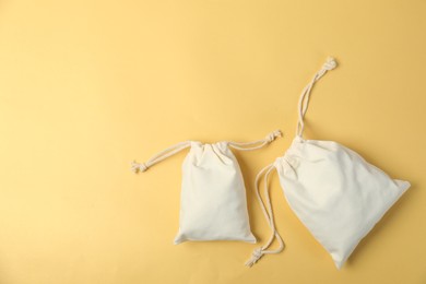 Photo of Two cotton bags on yellow background, flat lay. Space for text