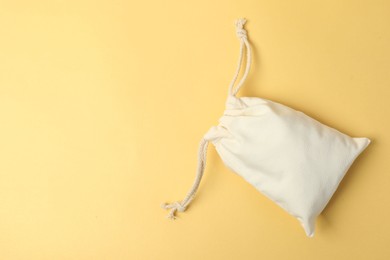 Photo of White cotton bag with ties on yellow background, top view. Space for text