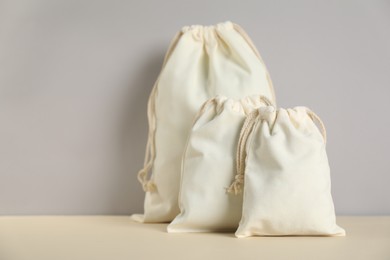 Photo of Cotton bags of different sizes on light table against grey background. Space for text