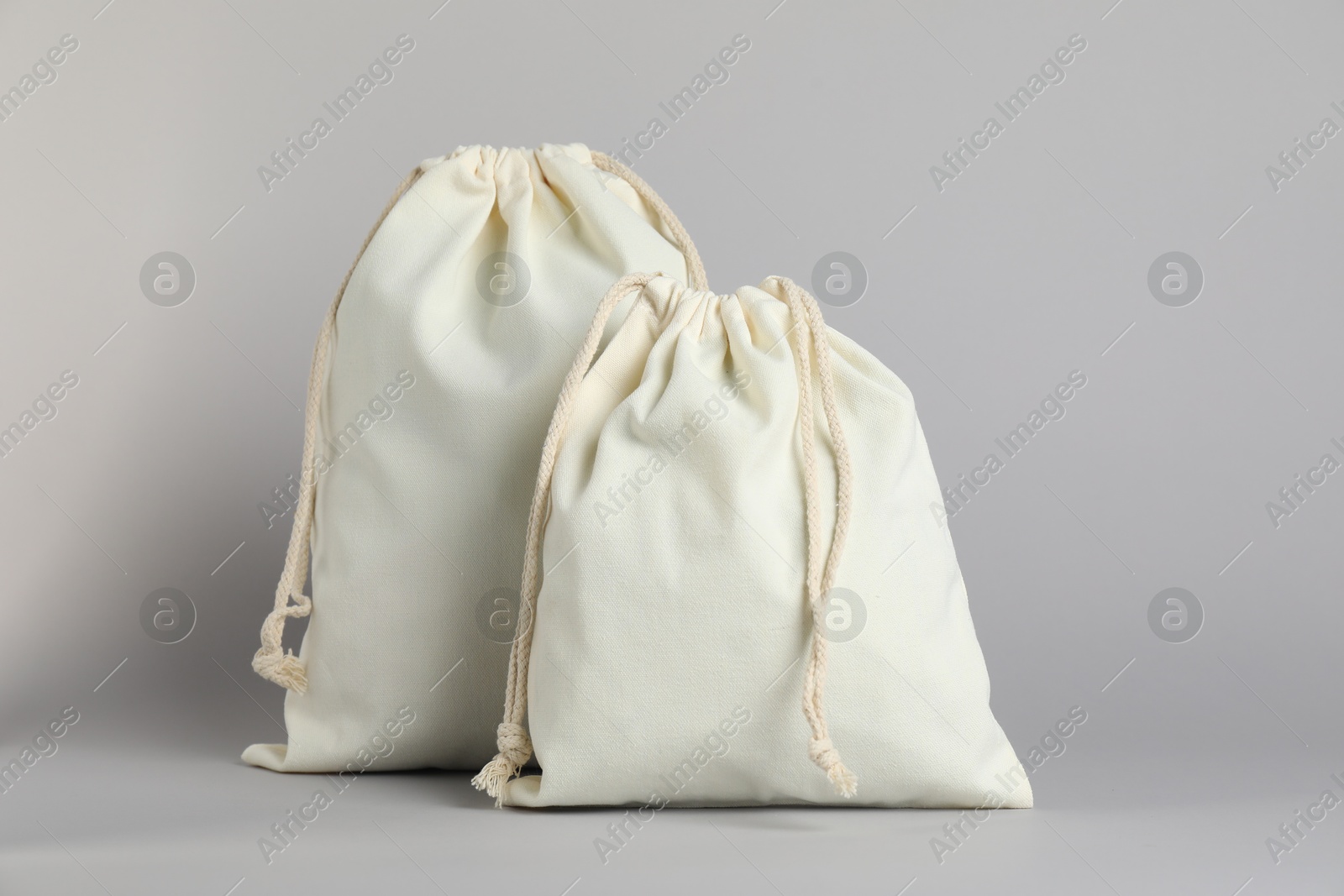 Photo of White cotton bags with ties on light grey background